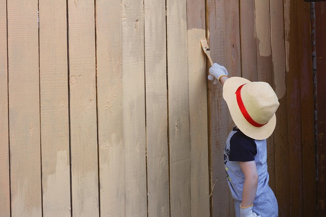 a customers chile helping to paint a fence in gilbert